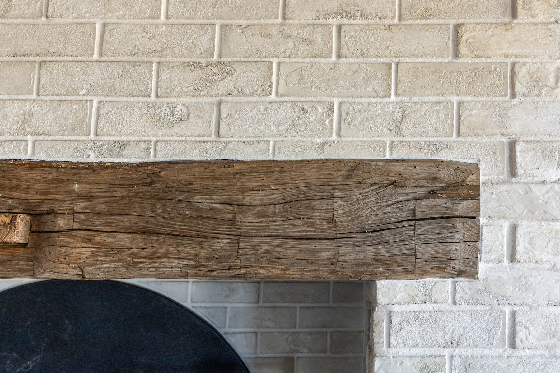Standard Brick Veneer in 2 by 8 Early Gray Limestone behind a reclaimed wood mantel in a Bonsall kitchen