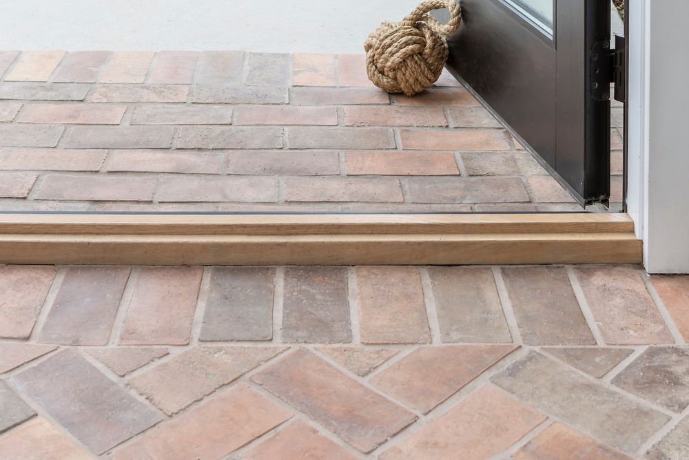 Swept Brick in 4 by 8 Normandy Cream running herringbone through a steel door to the patio