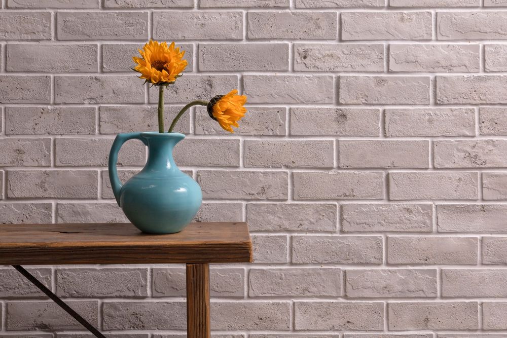 Standard Brick Veneer in 2 by 8 Early Gray Limestone behind a wood bench, sanded texture at eye level