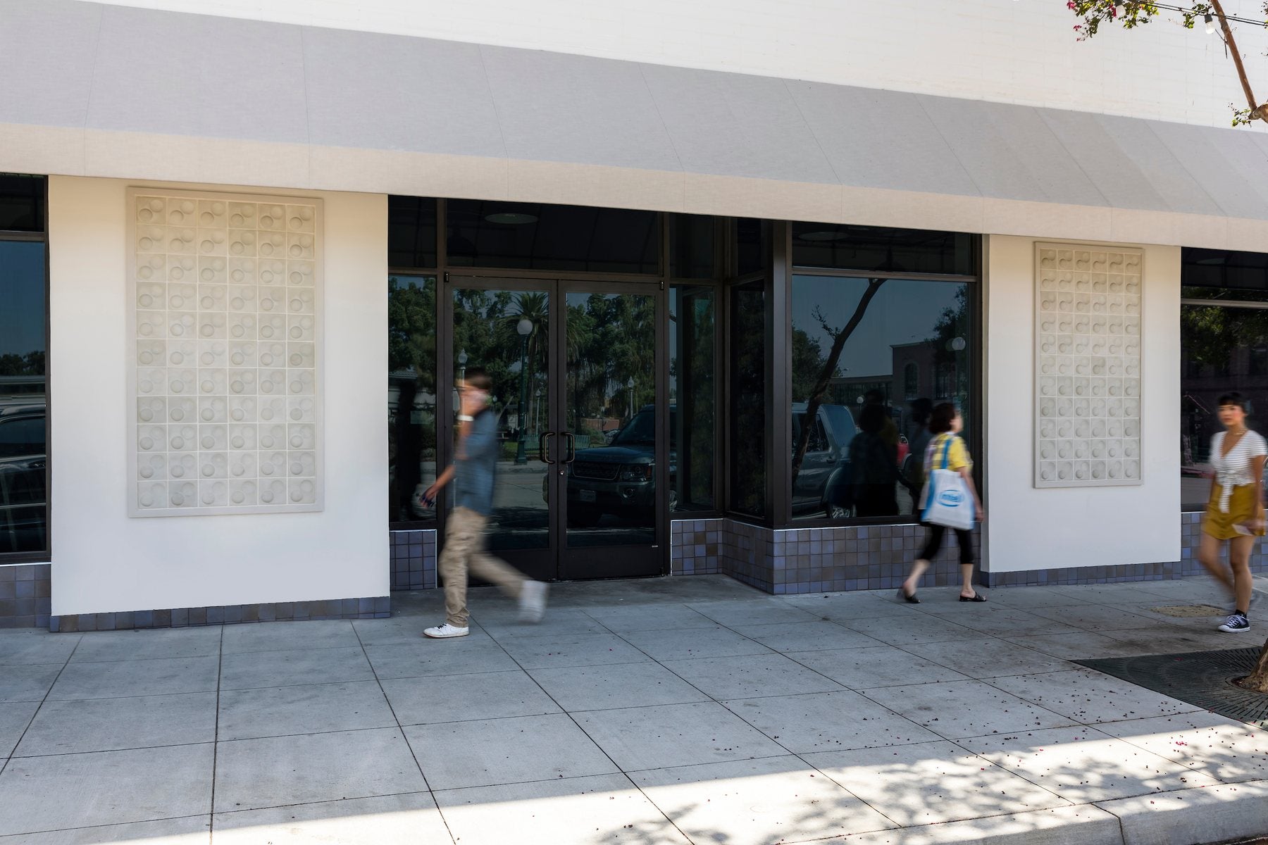 Two recessed panels of Corona 7x7 concrete cladding on a commercial storefront, with people passing