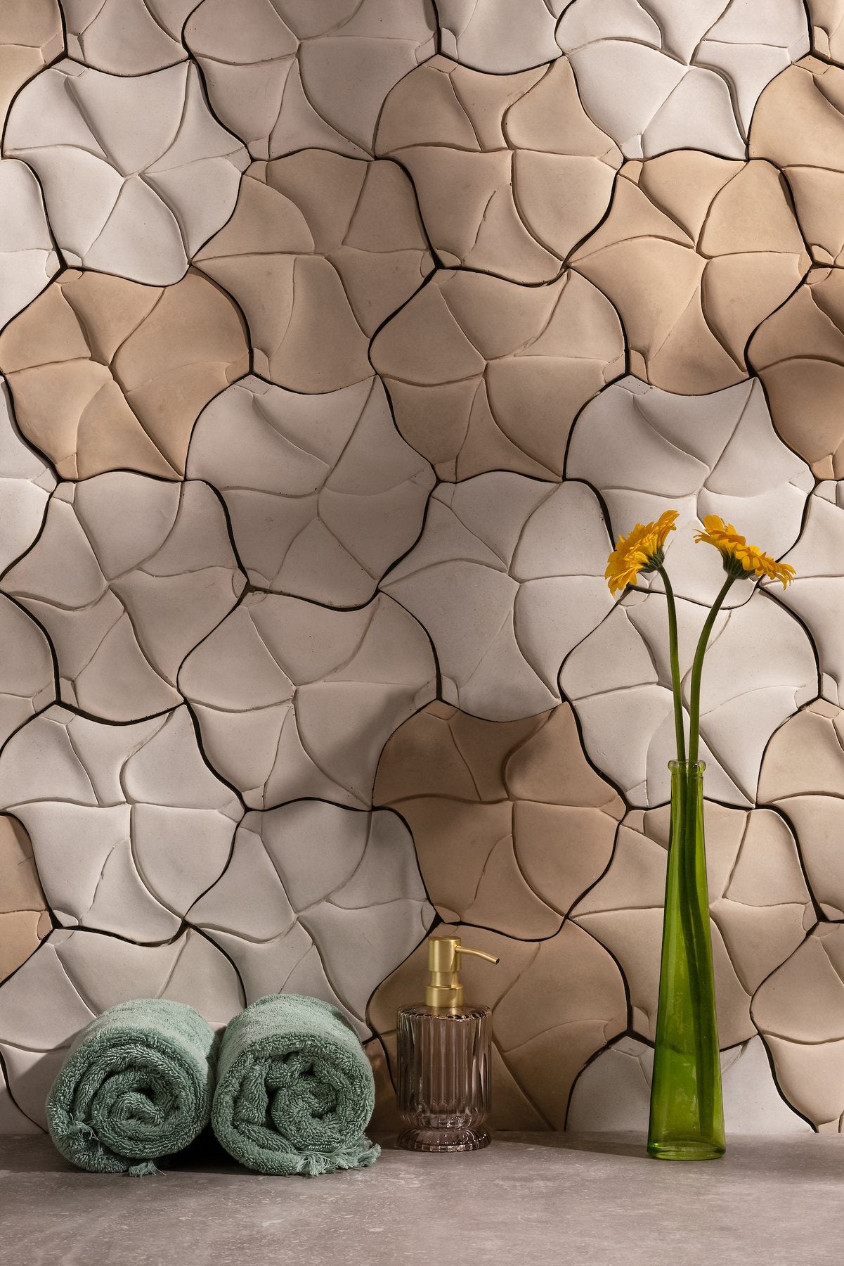 A Floways wall in five concrete colors behind rolled towels and a vase of flowers