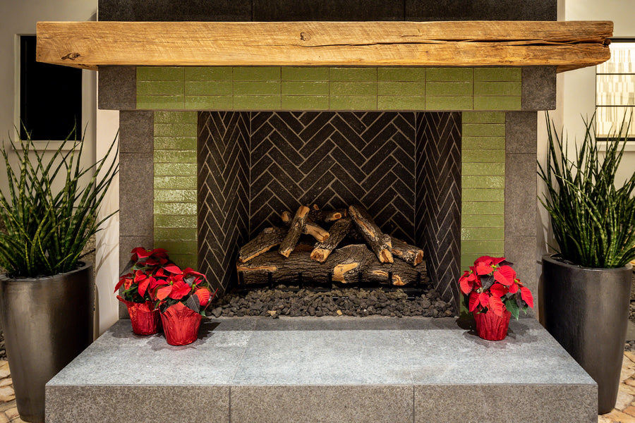 A fireplace surround of glazed brick in Jalapeno under a heavy timber mantel