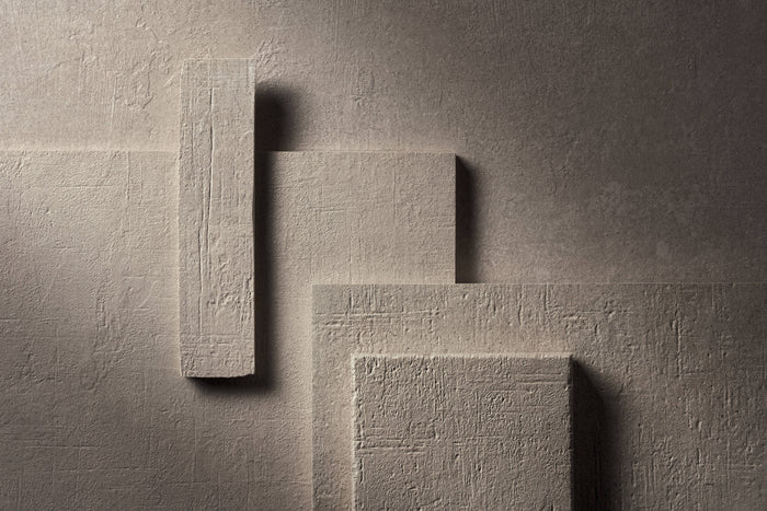 The same arrangement of Terra Crea pieces in Duna, a sand tone, lit hard from the side against a dark ground