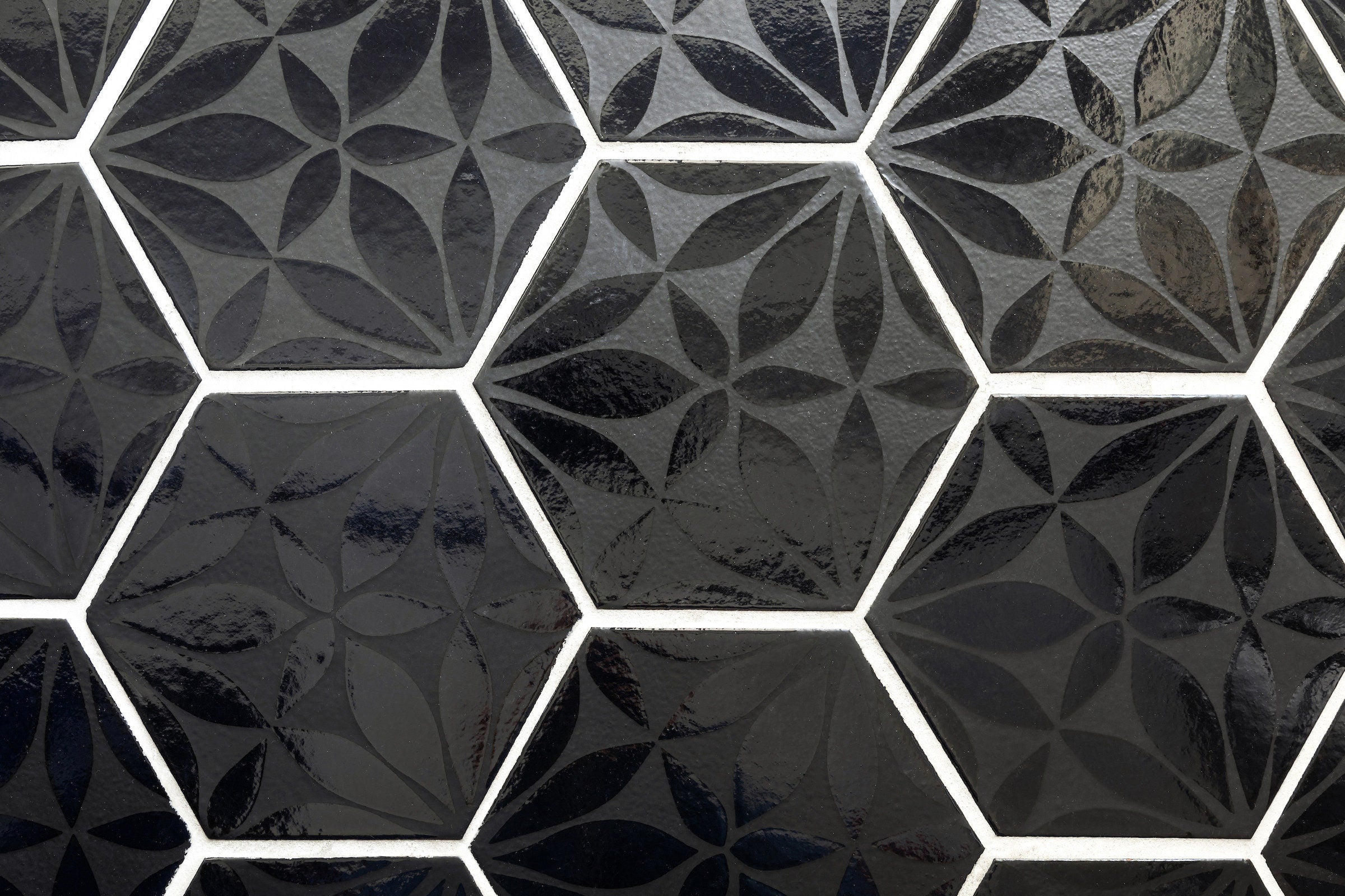 A field of black Silk Road hexagons, the same six petal design repeating across every tile, set with white grout