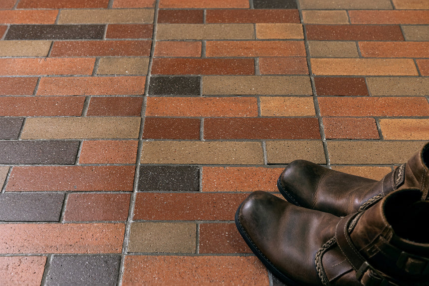 Pair of brown boots on a patterned brick pavement